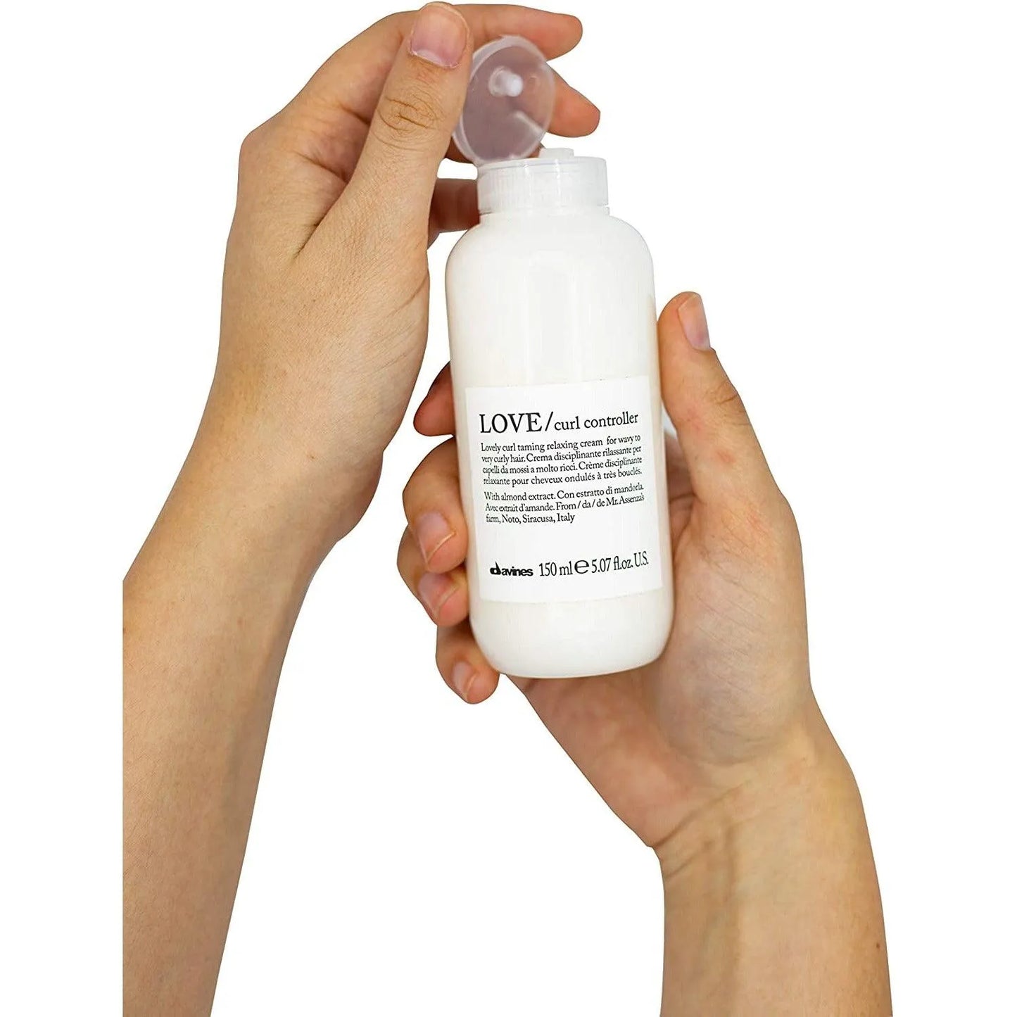 Hands holding a bottle of LOVE curl controller cream for wavy and curly hair, 150ml.