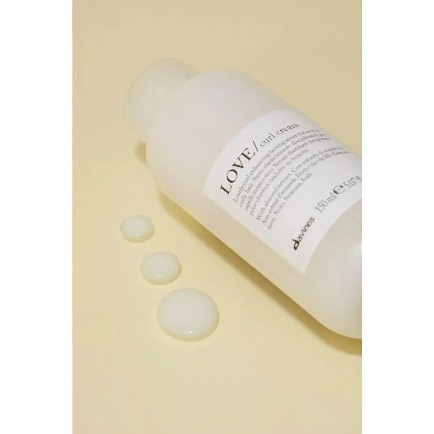 Davines LOVE curl cream bottle with cream texture drops on a beige background