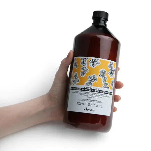 Hand holding Davines Nourishing Keratin Wonder Superactive 1000ml hair care bottle