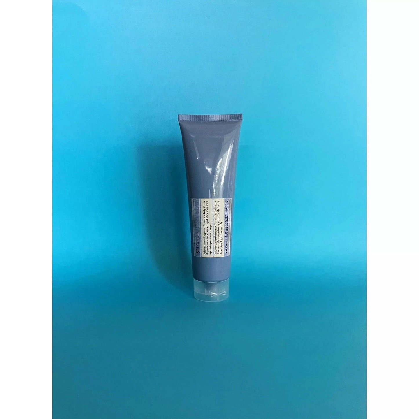 Purple tube of after sun cream with label, standing on blue background