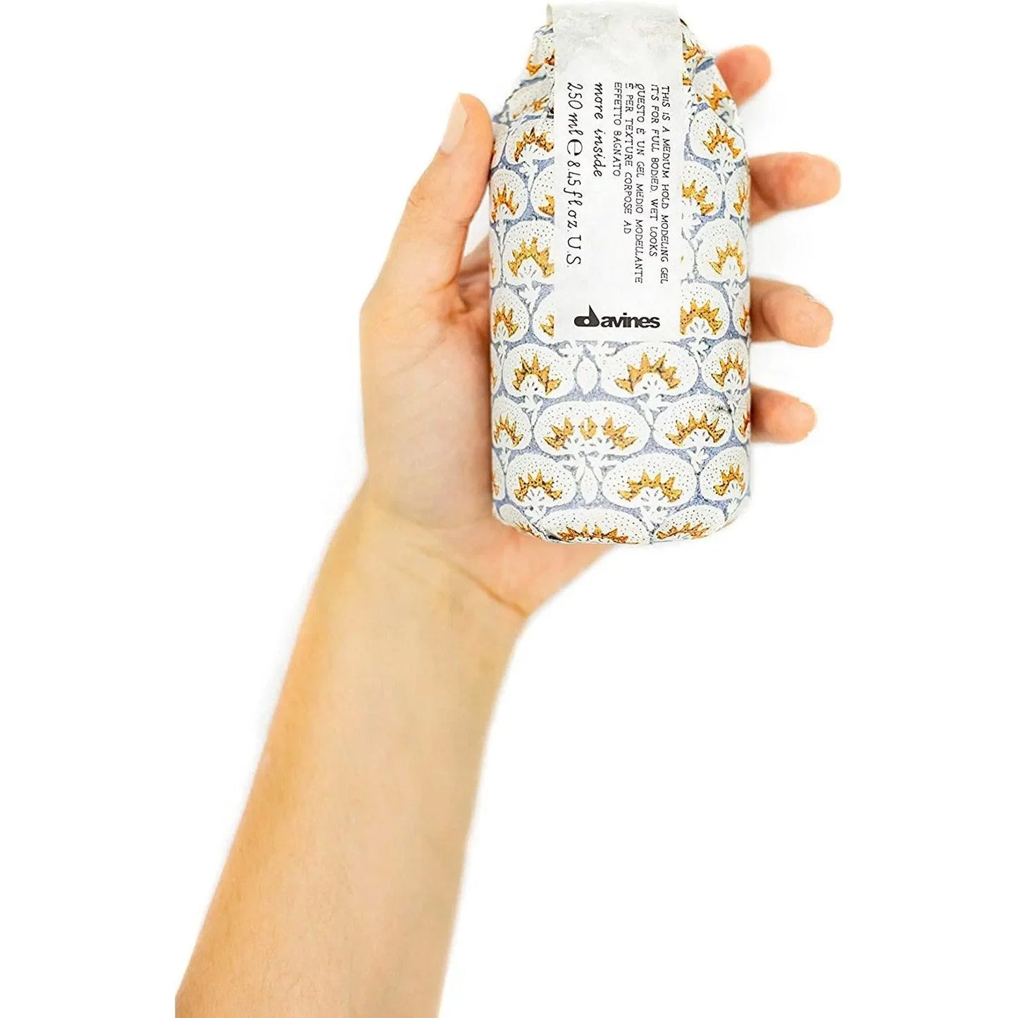 Hand holding a patterned Davines medium hold modeling gel bottle for hair styling