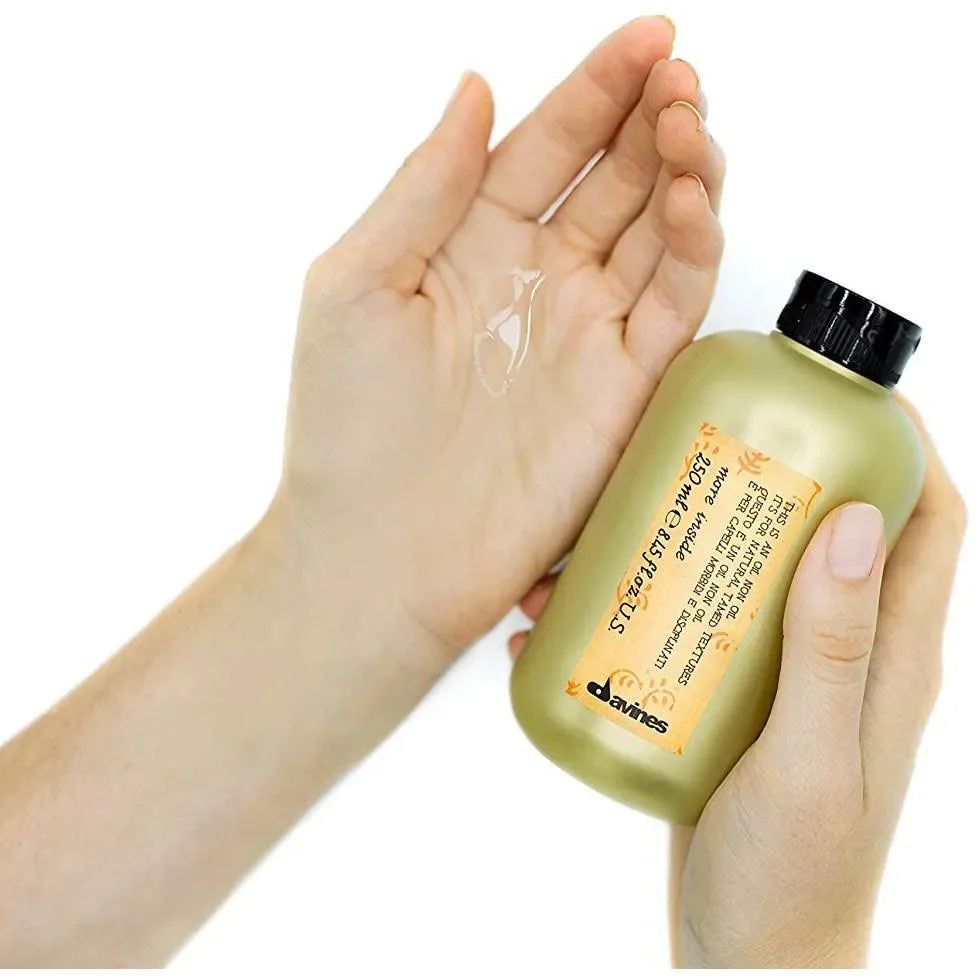 Person applying Davines hair oil non oil from gold bottle onto palm