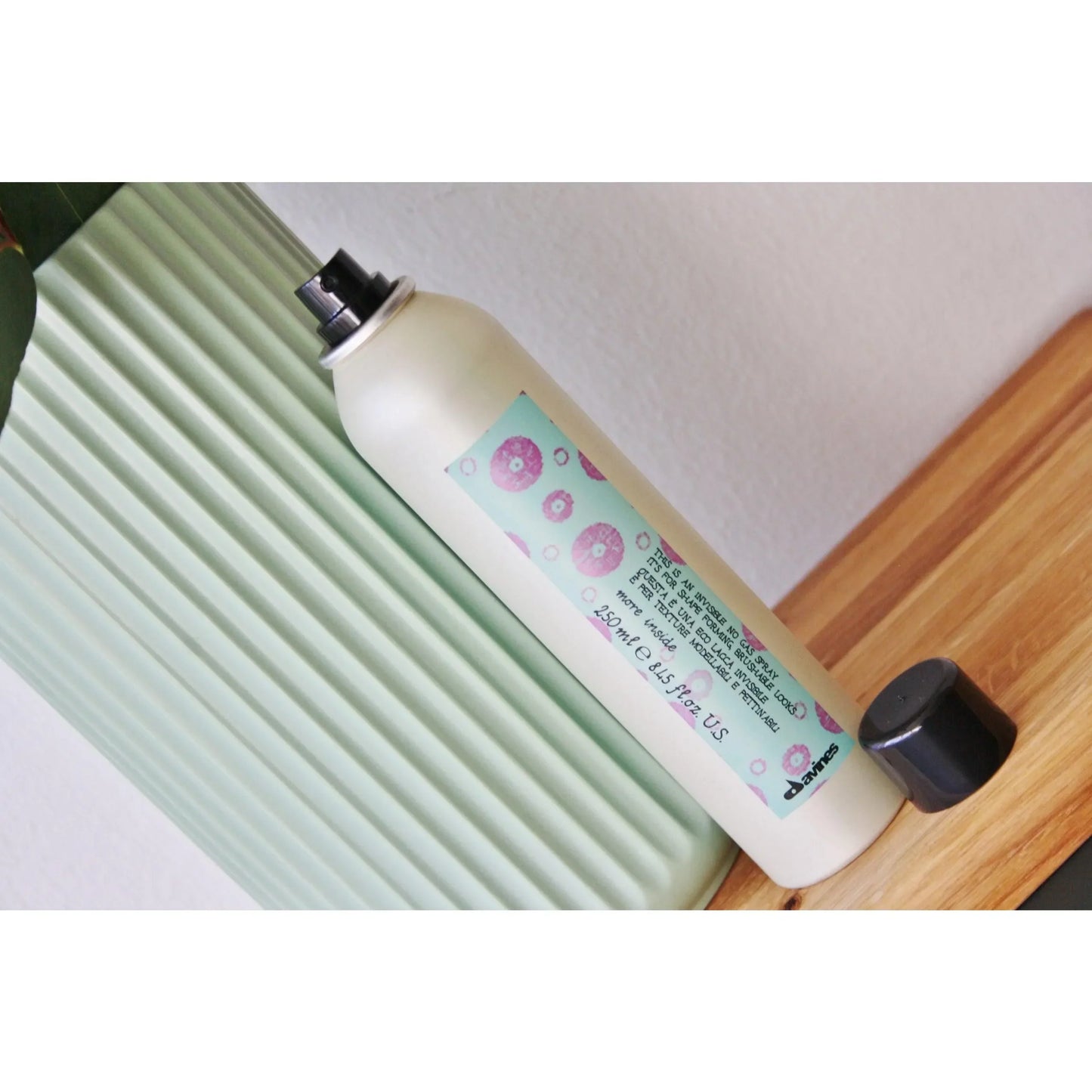 Davines hair spray canister with colorful label on wooden surface, haircare product photography