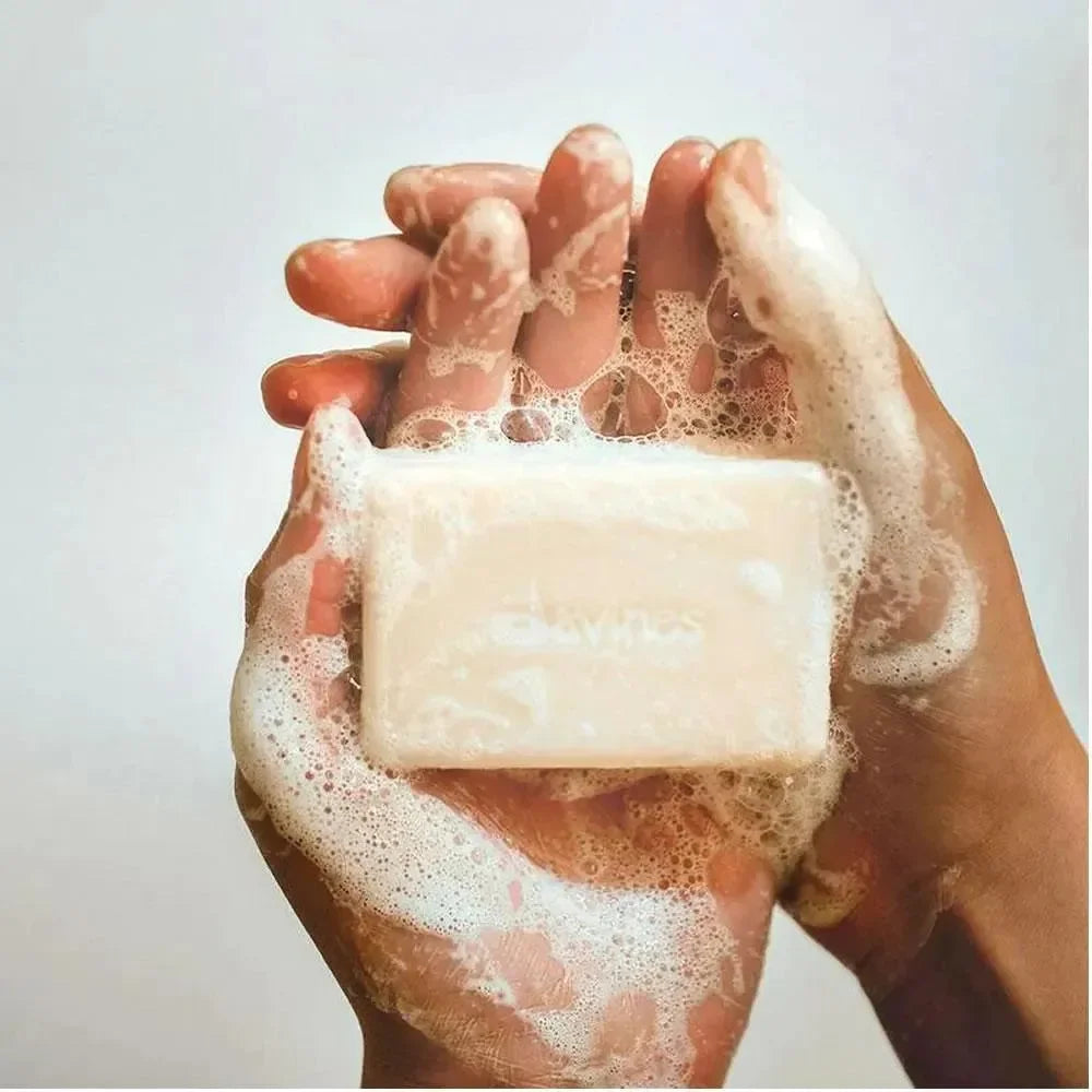 Hands holding a lathered rectangular shampoo bar for haircare