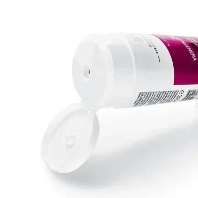 Opened tube of hair thickening balm with white cap, close-up on product nozzle.