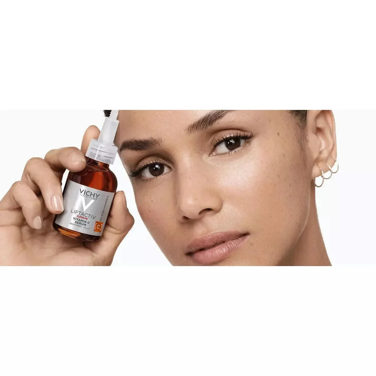 Woman holding Vichy Liftactiv Vitamin C Serum bottle close to her face, skincare concept