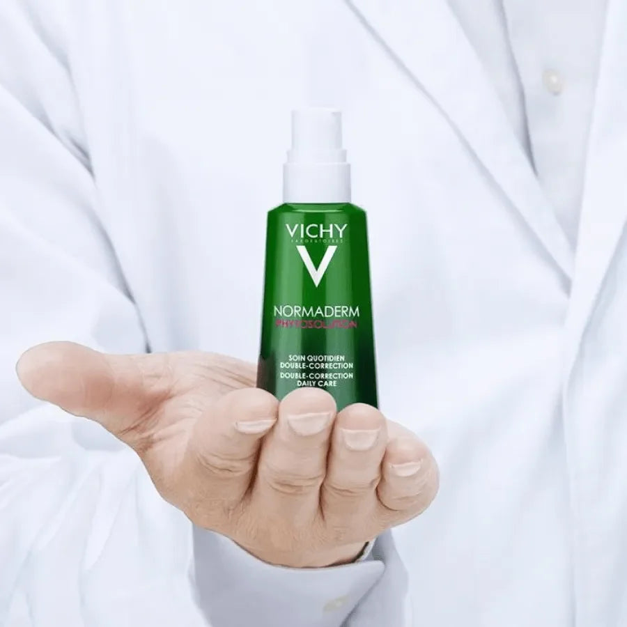 Vichy Normaderm Phytosolution anti-blemish skincare bottle held by a person in a white coat