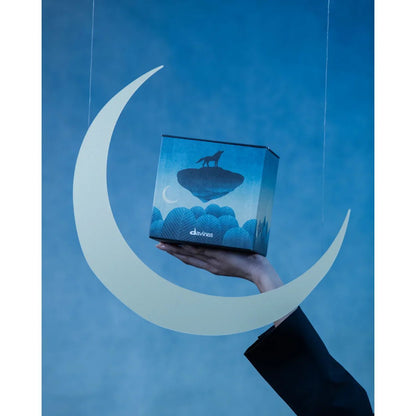 Hand holding Davines Precious Temperate Forest set box with wolf design, moon cutout, blue background. Goldfarmaci skincare Albania.