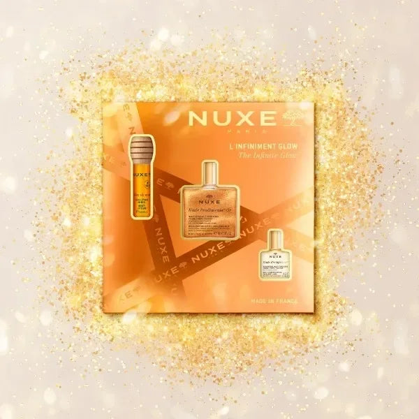 Nuxe The Infinite Glow Set skincare gift box with gold shimmer background at Goldfarmaci