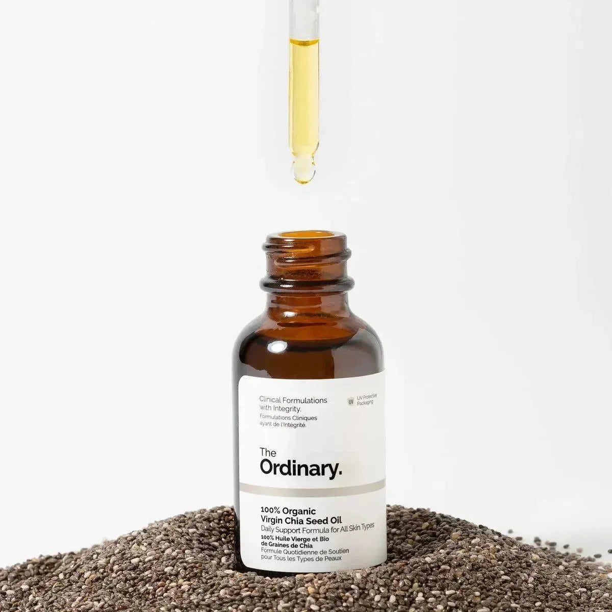 The Ordinary 100% organic virgin chia seed oil bottle with dropper, surrounded by chia seeds