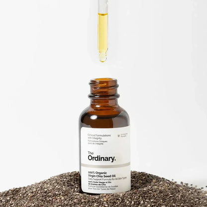 The Ordinary 100% organic virgin chia seed oil bottle with dropper, surrounded by chia seeds